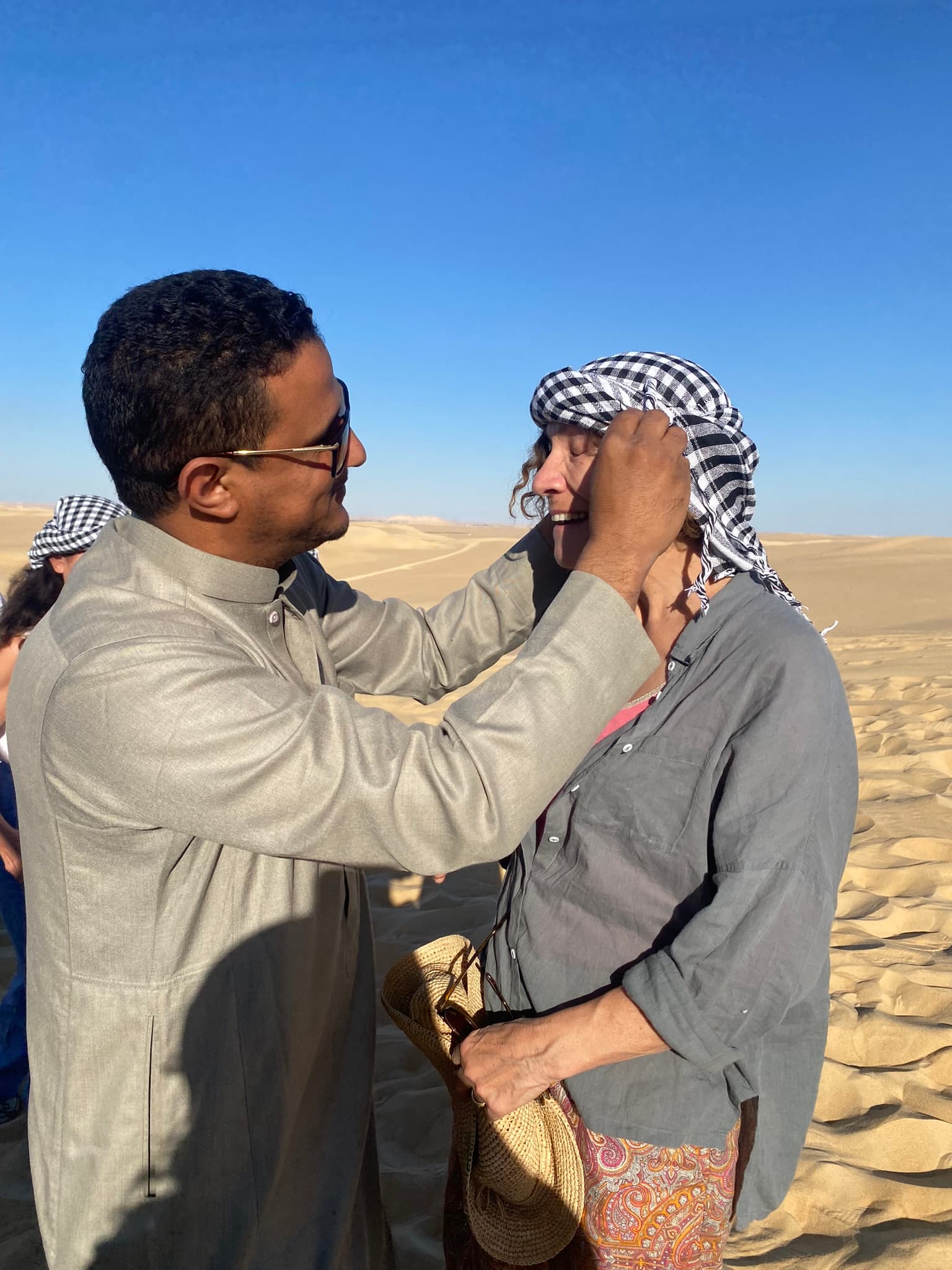 Guide local nouant le keffiyeh sur une voyageuse, soin et attention